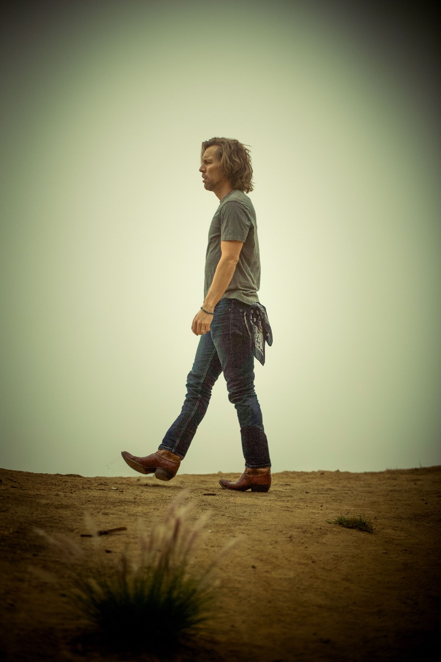 Shawn-Caulin Young walking in cowboy boots across an open hillside